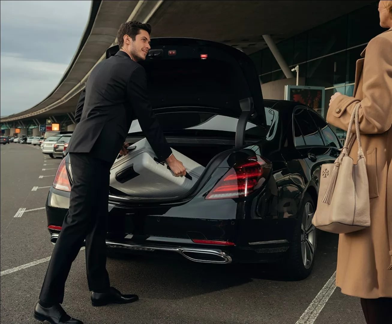 Chauffeur loading luggage into a Mercedes at Geneva Airport